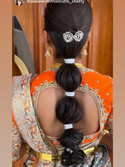 A modern and chic bubble ponytail, perfect for a Sangeet or reception. This sleek style is accented with a beautiful kundan hair clip, offering a contemporary twist on bridal hair.