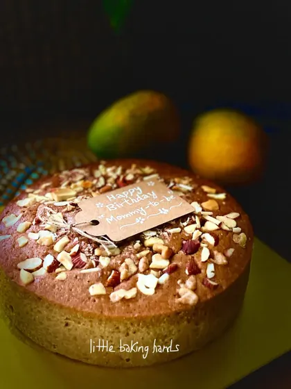 A side view of the vegan mango nuts cake, showing its lovely height and generous topping of nuts.