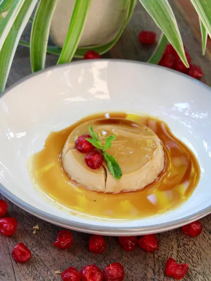 A wider shot of the caramel pudding, surrounded by fresh cherries. The presentation is as important as the taste.