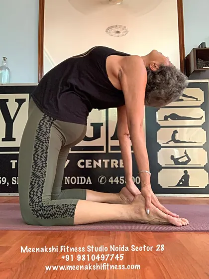 A slightly different angle of Camel Pose, showing the hands reaching for the heels to support the backbend.