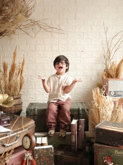 A moment of pure, expressive joy! This little boy throws his hands up with a big laugh, bringing so much life and personality to the vintage-themed set.