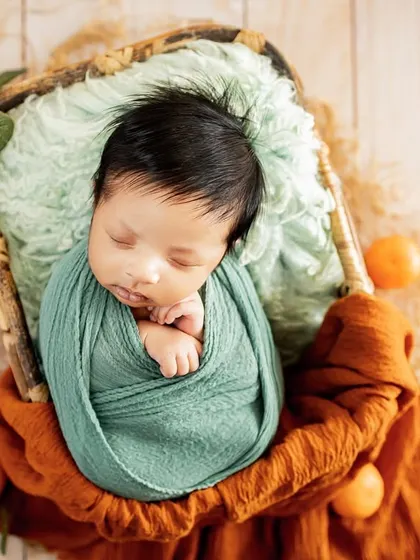 A pop of color with this citrus-themed newborn setup. Using natural elements like these small oranges adds a fresh and unique touch to the classic basket pose.
