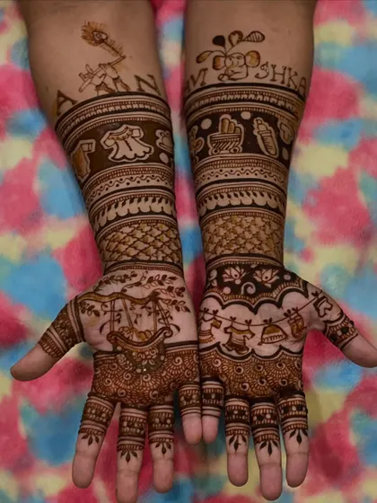 A special design for a baby naming ceremony, with the names "AARAV" and "ANSHIKA" written on the arms. The palms feature a cradle and other cute baby motifs.