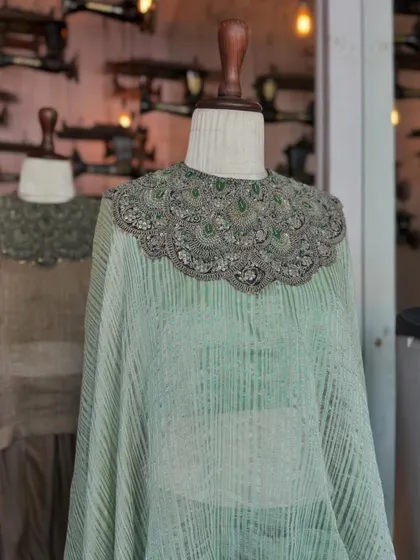 This flowing cape in a soft, textured green is defined by its stunning, heavily beaded collar. It's an effortlessly festive piece that is sure to turn heads.