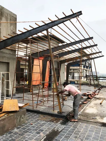 The steel skeleton for a rooftop pergola under construction. This image shows the raw strength and geometric precision of the steel I-beams and supports before the finishing layers are added.