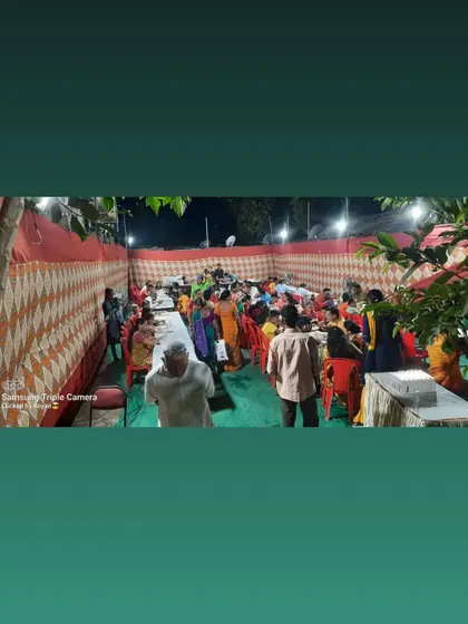 A wide shot of a community gathering inside a pandal in Airoli Gaon.