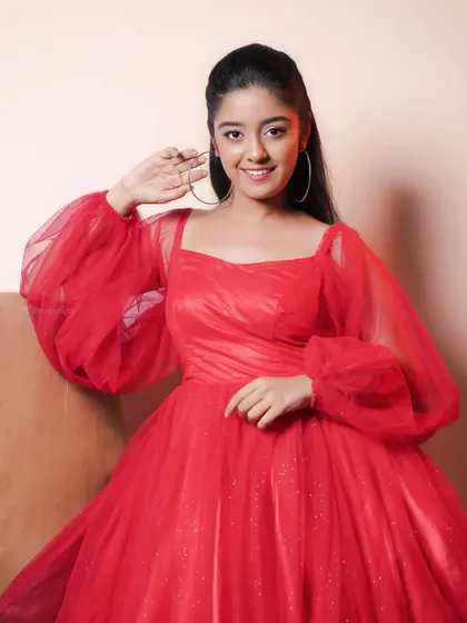 A portrait of an actress in a vibrant red tulle dress. The simple background and soft lighting make the color and texture of the dress stand out.
