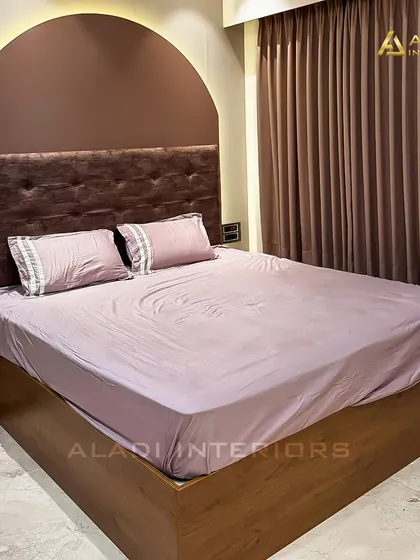 A cozy bedroom with a mauve color scheme. The arched, backlit headboard creates a soft and inviting focal point, complemented by matching bedding and curtains.