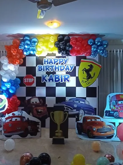 A high-octane Disney Cars theme with a checkered flag backdrop, character cutouts of Lightning McQueen and Mater, and a Ferrari logo for the birthday boy.