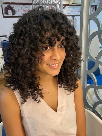 The curly shag with bangs is a versatile look for curly hair.