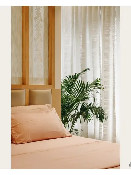 A detail of the bedroom's headboard and bedside area. The design incorporates natural wood and a potted plant, bringing organic elements into the room to enhance its tranquil feel.