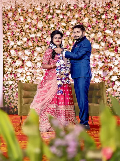 A classic wedding reception look. The couple stands against a beautiful floral wall, ready to greet their guests in a hall that I've decorated to feel grand and welcoming.