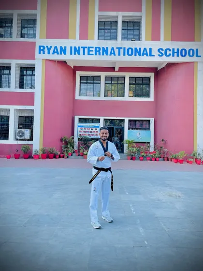 Standing outside Ryan International School. My goal is to reach as many students as possible, equipping them with the skills to feel safe and confident.
