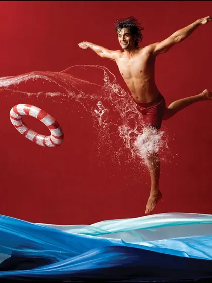 A dynamic and conceptual shot that uses a vibrant red background and a splash of water to create a sense of action and excitement. This style is perfect for activewear or swimwear brands.