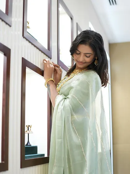 Sonu admiring the jewelry, her elegant saree providing the perfect canvas.