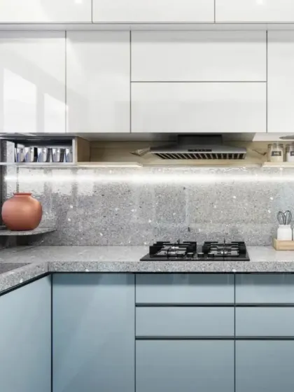 A modular kitchen with light blue cabinets and a terrazzo-style countertop. The under-cabinet lighting ensures a well-lit workspace.