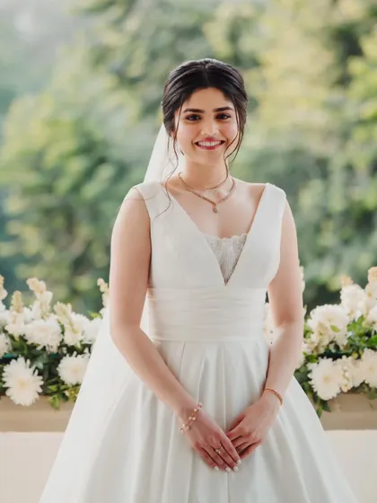 A picture of pure bridal joy. Her hair is elegantly styled in a low bun, and her makeup is fresh, clean, and radiant.