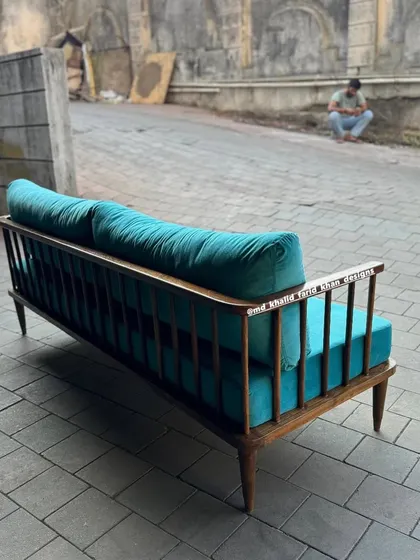 A mid-century style sofa with a spindle back, upholstered in a bright turquoise fabric.