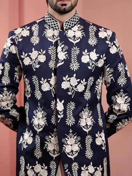 A close-up of the intricate white floral embroidery on the navy jacket. The craftsmanship is evident in every stitch, creating a wearable piece of art.