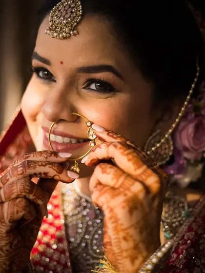 A close-up of the bride, Priyanka, as she puts on her nath, a beautiful and traditional getting-ready moment.