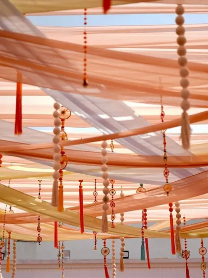 The ceiling decor for the Phulkari Mehendi, featuring layers of soft, flowing drapes and delicate hanging tassels, creating a dreamy and colorful canopy.