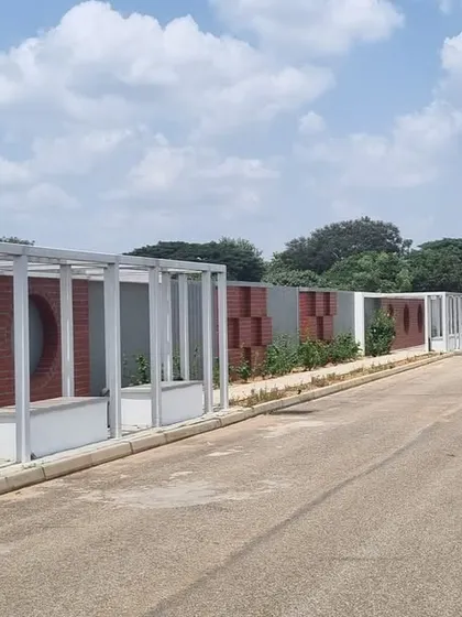 The entrance to Aamby City in Hoskote, where we designed the streetscape and boundary walls. The design uses a modern framework with brick accents and integrated planters to create a welcoming first impression.