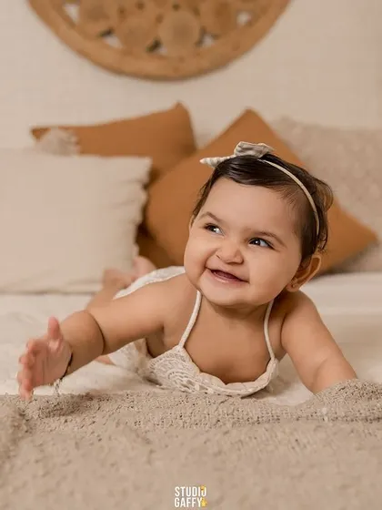 A happy baby girl lying on her tummy, her joyful expression lighting up the frame.