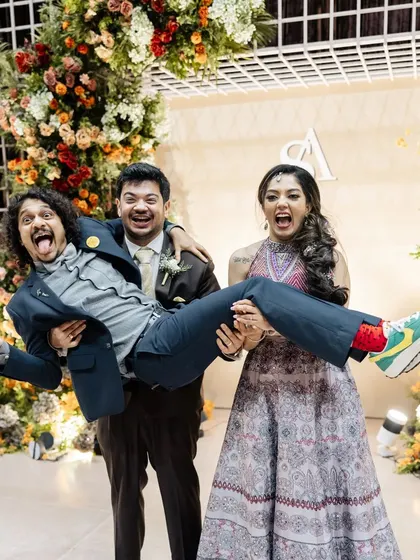 Fun and playful moments are what make a wedding memorable. Guests celebrate in front of a beautiful floral archway, showing the decor in action.