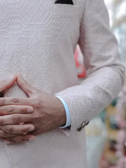 A close-up shot focusing on the details of the groom's textured pink bandhgala jacket. We believe the details of the outfit are an important part of the story.