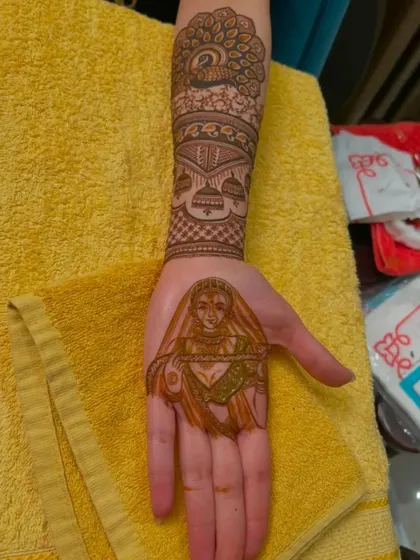 A lovely bridal portrait on the palm, with peacock and jhumka designs on the arm.