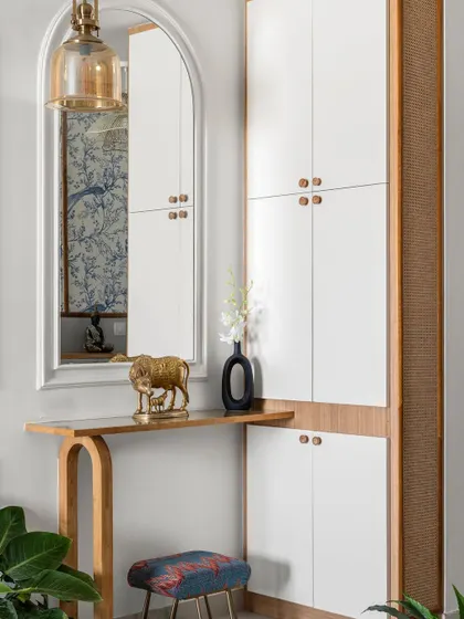 We split the foyer storage into two units. This one features a sleek console table with an arched mirror, which is both practical and makes the space look much bigger.