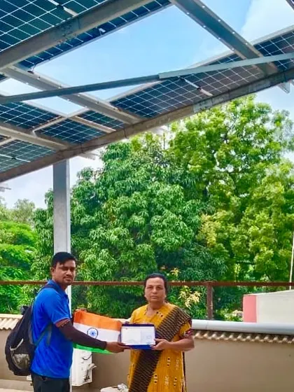 A customer receives her certificate from our team member, celebrating her home's new solar power system with the tricolor.
