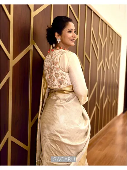 The back view of Pooja's ensemble, showing the intricate jari thread embroidery on the off-white velvet jacket.