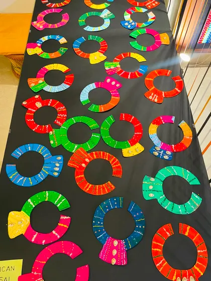 A stunning table display of African Masai-inspired neck collars, crafted with vibrant colors and patterns by our students.