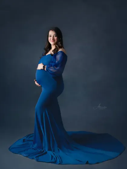 A full-length solo portrait showcasing the beautiful train of this royal blue maternity gown. The simplicity of the pose exudes confidence and grace.