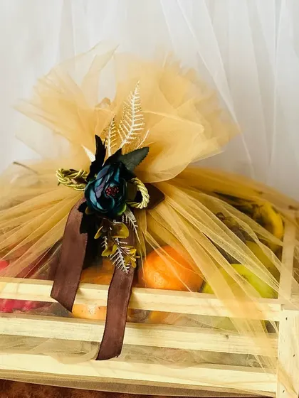 A simple yet beautiful fruit basket wrapped in golden net with a dark floral accent. This "basket full of health and happiness" is a perfect gift for any occasion.