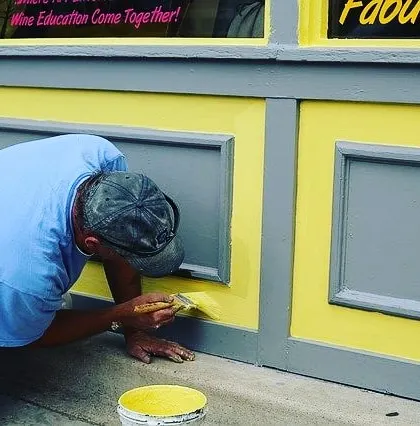 A painter carefully applying a fresh coat of yellow paint to a storefront. I handle detailed work for retail and commercial exteriors to ensure they look professional and inviting.