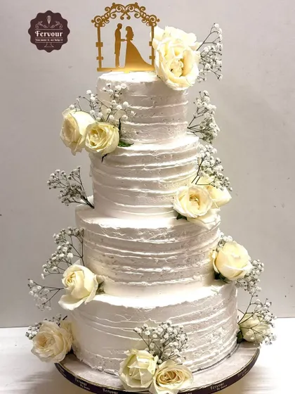 Simple elegance is showcased in this four-tier wedding cake. The textured whipped cream frosting is adorned with fresh white roses and baby's breath, proving that sometimes the most beautiful designs are the most classic.