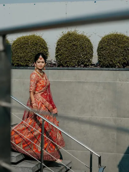 A full-length shot of the bride walking down the stairs. This dynamic photo captures the flow and elegance of her lehenga in motion.