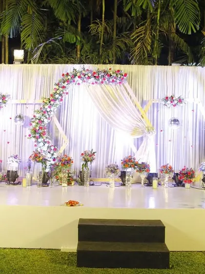This elegant white and floral stage was designed for an outdoor evening celebration. The flowing drapes, floral arch, and standing light-up flowers created a dreamy and romantic ambiance under the stars.