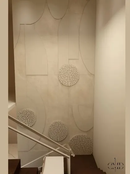 A close-up of the textured wall art in the foyer, which features abstract shapes and stone-like circular elements.
