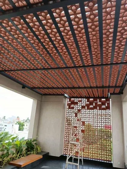 A closer look at a custom-built pergola roof combining a strong metal frame with decorative terracotta jali blocks. This design allows for air circulation while providing filtered sunlight.