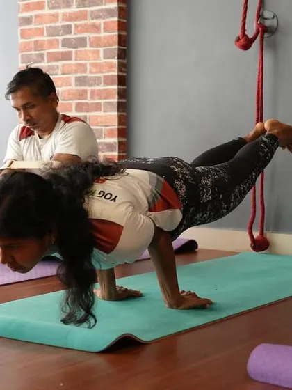 A student demonstrates impressive arm strength and balance in Eka Pada Koundinyasana II, a testament to her dedication.