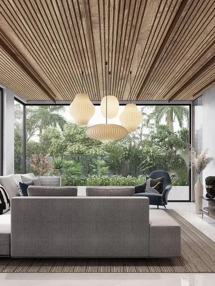 This living room is designed to feel like a tranquil pavilion, with floor-to-ceiling glass walls that open completely to the surrounding tropical landscape. The slatted wood ceiling adds warmth and texture, enhancing the indoor-outdoor connection.