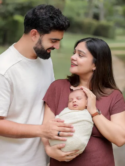 A beautiful outdoor portrait of new parents with their newborn. The soft, natural light of the park and the genuine smiles make this a truly special memory.