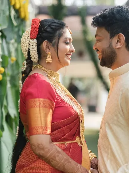 A South Indian couple shares a sweet, smiling glance. Set against a backdrop of banana leaves and marigolds, this frame is a beautiful representation of traditional love.