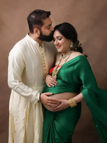 A portrait of love, tradition, and family. The husband's tender kiss on his wife's forehead, both dressed in beautiful ethnic attire, makes for a truly heartwarming image.