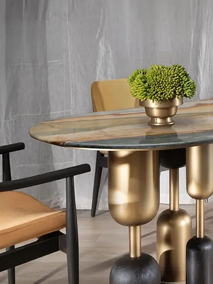 A close-up of our Lotus Quartz dining table. The beautiful, painterly stone top is supported by a sculptural base of solid teak wood and antique-finished brass, creating a stunning centerpiece that is both functional and a work of art.