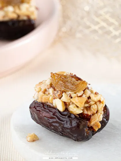 A macro shot of a stuffed date. The close-up perspective and bright lighting highlight the rich texture of the date and the crunchy nut filling, making a small item look incredibly luxurious.