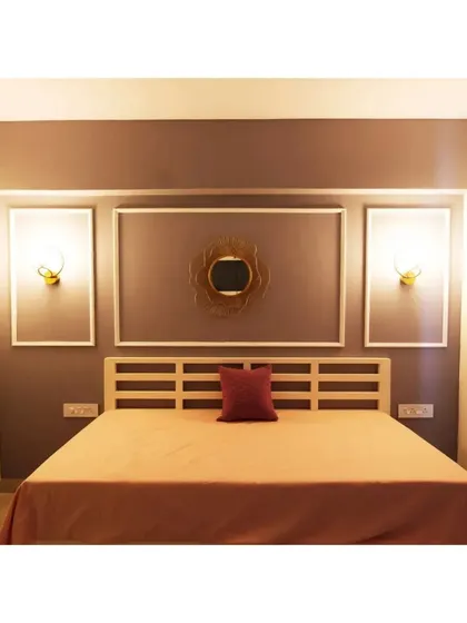 A modern bedroom with a slatted wood headboard and elegant wall molding. The warm, ambient lighting from the wall sconces creates a relaxing and sophisticated mood.